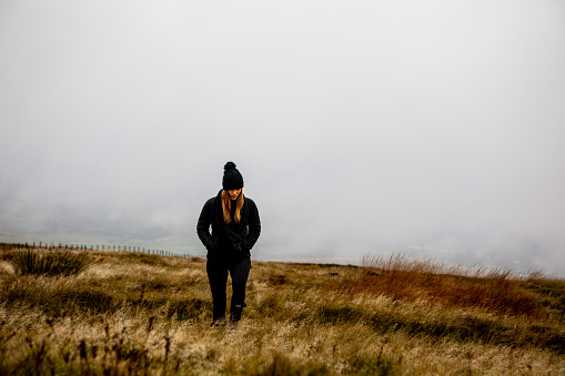 Beautiful Caucasian Woman Walking in Open Field in the Fall in Manchester England Heavy Fog and Overcast. Mental Health Awareness. Copy Space.