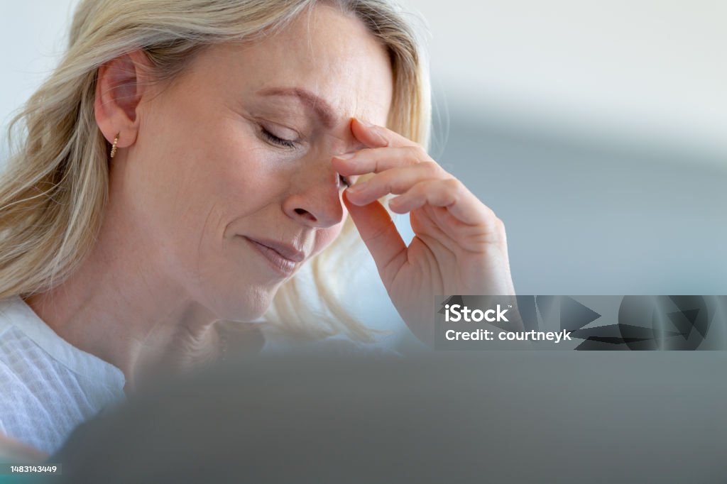 Upset stressed mature woman close up. Upset stressed mature woman close up. She looks worried and in pain. She is about to cry Headache Stock Photo