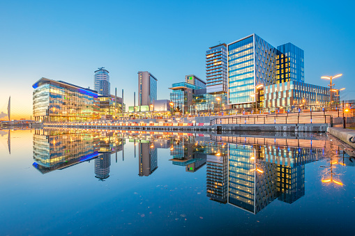 Office buildings and apartments in the Salford Quays area of Manchester, England, United Kingdom at twilight blue hour.