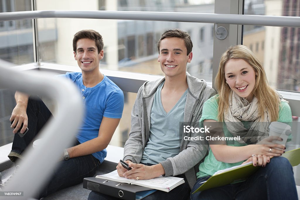 Ritratto di un sorridente studenti universitari seduti in finestra - Foto stock royalty-free di 20-24 anni