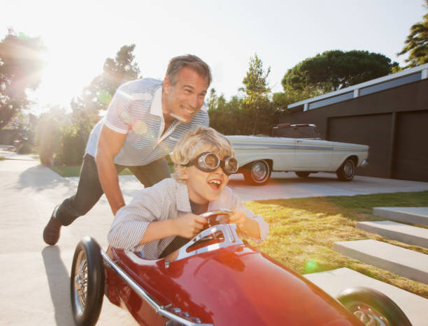 father pushing son in go cart - 50 54 jaar fotos stockfoto's en -beelden