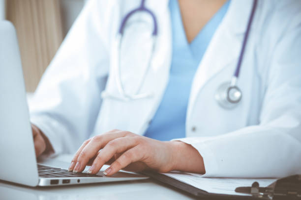 istock Unknown woman-doctor typing on laptop computer while sitting at the table. Medicine concept 1483160134