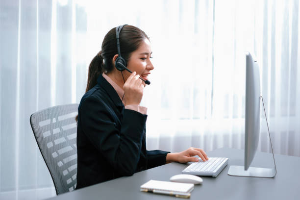 istock Enthusiastic asian call center with headset and microphone working on her laptop 1483166995