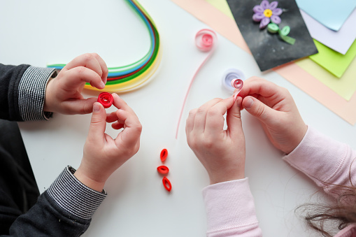 Children's activities, hands with paper top view, quilling technology.
