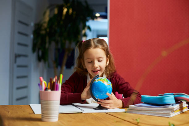 istock Happy schoolgirl at workplace studying globe in classroom 1483170200