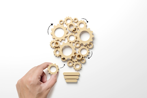 Business process and workflow automation with flowchart. Hand holding wooden cog flowing process management lightbulb shape on white background