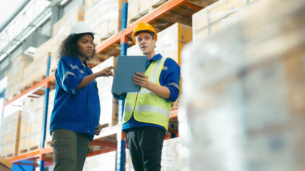 istock Smiling workers in distribution warehouse having a cheerful conversation. They wearing vest and safety helmet in work 1483172316