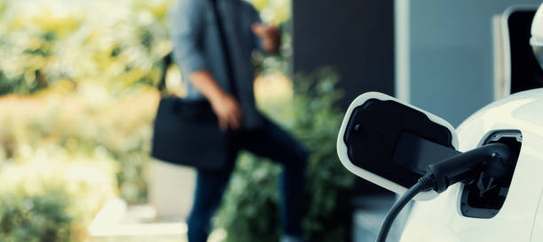 istock Focus EV charging station at home with blur progressive man in background. 1483175351