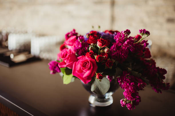 Wedding bouquet containing primarily pink roses, with purple, green and yellow highlights.  Blurred behind bouquet.