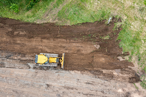 heavy construction machine is leveling the land. bulldozer is moving and flattening soil. aerial top view.