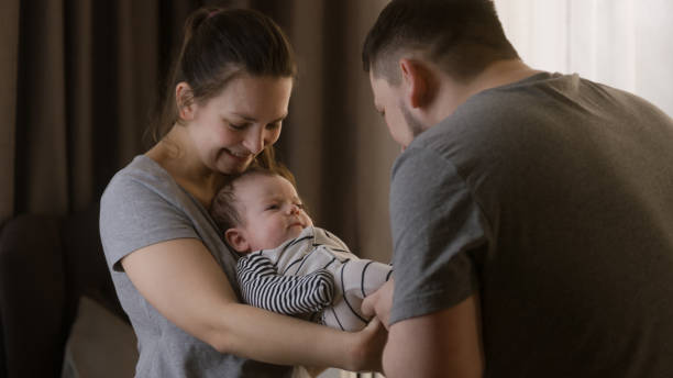 istock Dad plays with legs of infant in bodysuit 1483184721