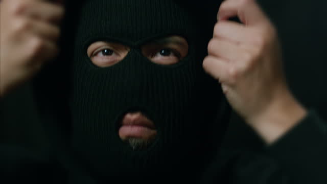 Latino Male Criminal Puts on Ski Mask and Hood, Then Nods Head Looking Around
