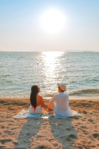 A couple enjoying a beach vacation at a tropical resort with a beautifully landscaped coastal pool at sunset. honeymoon destination at Thailand