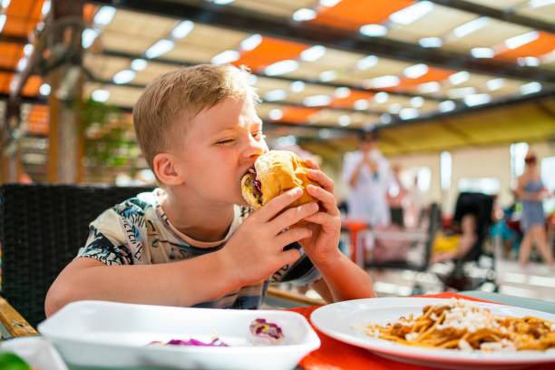 istock the boy is having lunch in a street cafe. a child eats a burger. children's menu 1483190317