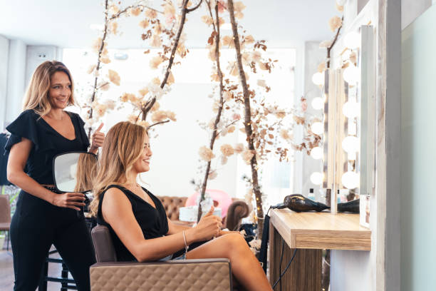 Hairdresser attending a beauty blonde woman in a hair salon stock photo