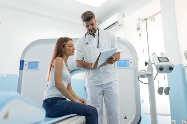 male doctor giving information to woman before mri scan examination. magnetic resonance imaging technology in specialized medical clinic. - x ray image radiologist examining using voice imagens e fotografias de stock