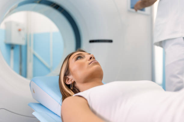 istock Female Patient Lying on a CT or PET or MRI Scan Bed, Moving Inside the Machine While it Scans Her Brain and Vital Parameters. 1483193393