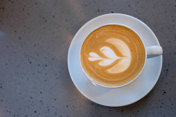 mouth-watering leaf is drawn on foam of delicious coffee Americano cappuccino insert spoon is removed drop falls into cup wonderful process for cooking show cooking and tasting coffee beans