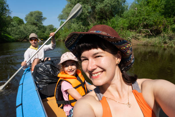 Man and woman couple, baby is sleeping, selfies are happy in family kayak trip rowing boat on the river, water hike, a summer adventure. Eco-friendly and extreme tourism, active and healthy lifestyle Man and woman couple, baby is sleeping, selfies are happy in family kayak trip rowing boat on the river, water hike, a summer adventure. Eco-friendly and extreme tourism, active and healthy lifestyle couple punting stock pictures, royalty-free photos & images