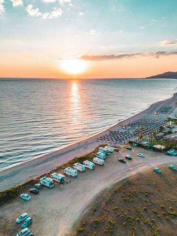 Drone shot of camper on the beach at sunset in Greece.