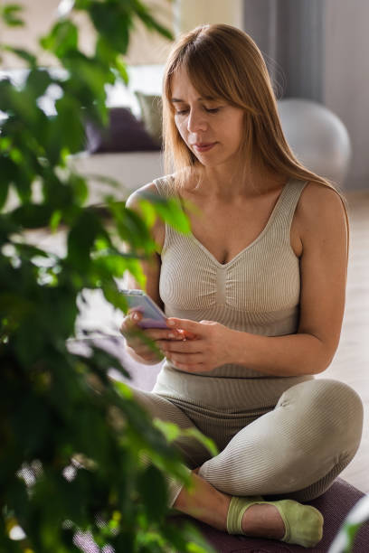 istock Trainer relaxing on yoga mat with smartphone after her workout in her pilates studio, checking new videos online. Caucasian woman taking break after yoga practice. Active lifestyle concept. 1483202868