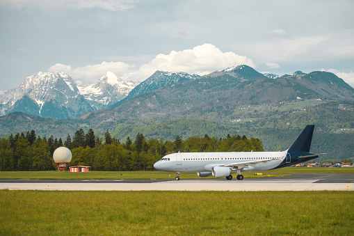Commercial airplane moving towards a runway at the airport. Doppler radar and beautiful Alps in the background.