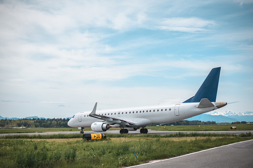 Commercial airplane moving towards a runway at the airport. Beautiful Alps in the background.