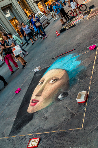 Florence, Italy - August 13, 2016: Pavement artists painting Girl with a Pearl Earring originally painting by Johannes Vermeer with chalk and pastels on the street of Florence