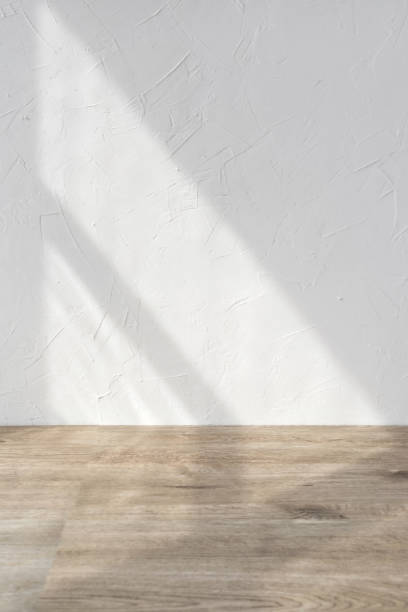 istock Sun light shadows on white textured wall and beige wooden floor, blank design template for home room interior or product stand mock up, business brand advertisement background, copy space 1483204413