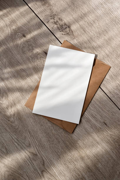 istock Blank paper card and envelope with mockup copy space and aesthetic sunlight floral shadows on neutral beige wooden table, minimalist business branding, invitation, greeting card template 1483204719