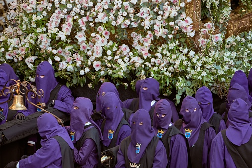 A group of people in the vestments of the holy week of Astorga in Spain carrying religious steps on their shoulders.