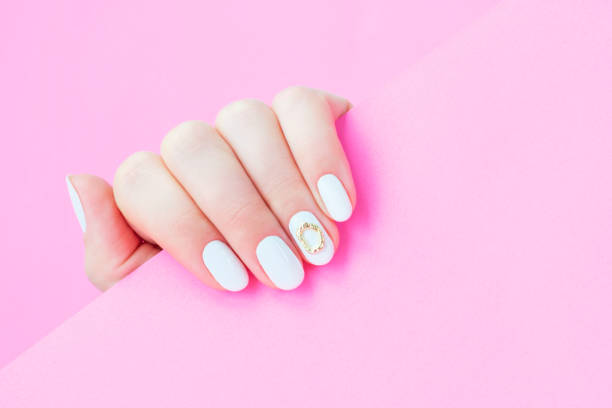 istock Female hand with white manicure on pink background, top view. 1483208219