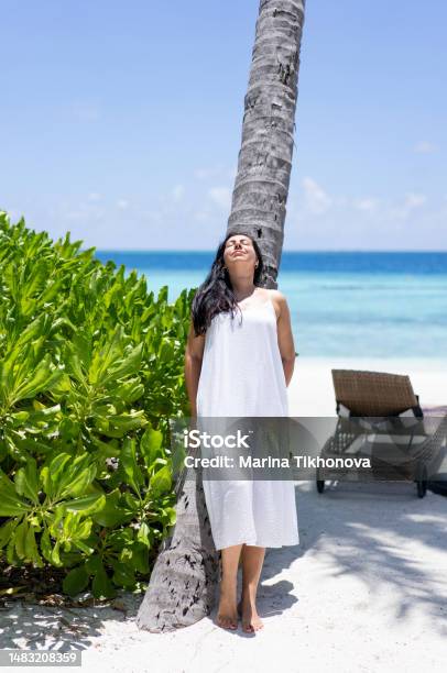 A Young Woman With Long Hair Stands Near A Palm Tree In Maldives And Exposes Her Face To The Sun Stock Photo - Download Image Now