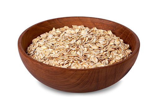 Rolled oats or oat flakes in wooden bowl isolated on white background with clipping path