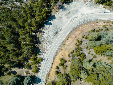 Aerial shot of winding asphalt road in woodland