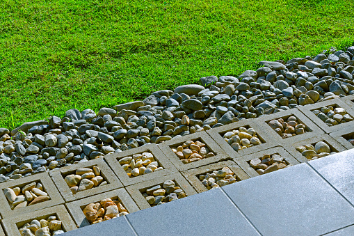 A modern staircase edge with contrasting grass and white pebbles