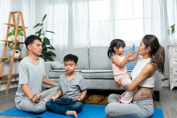 부모, 아들, 딸로 구성된 아시아 가족은 집 한가운데서 행복하게 휴식을 취하고 있으며, 출산 직전에 큰 배를 임신한 아름다운 십대 어머니가 딸과 놀고 있다. - torso physical therapy patient relaxation exercise 뉴스 사진 이미지