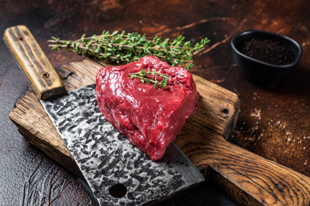 istock Raw rump steak on a butcher cutting board. Dark background. Top view 1483216429
