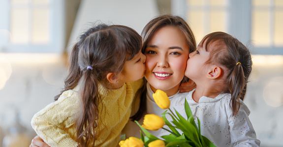 Happy mother's day. Children daughters congratulating mother and giving her bouquet of flowers.