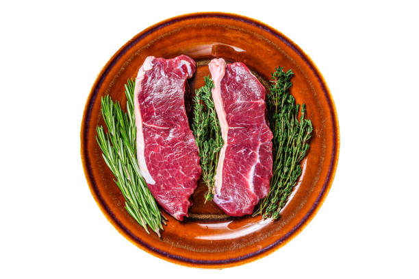 istock Raw  strip loin beef meat steak on a plate with herbs.   Isolated on white background. 1483219615