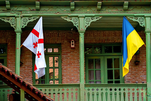 Georgian and Ukrainian flags hanging on the balcony of a classic Georgian wooden house in the center of Tbilisi in Georgia.