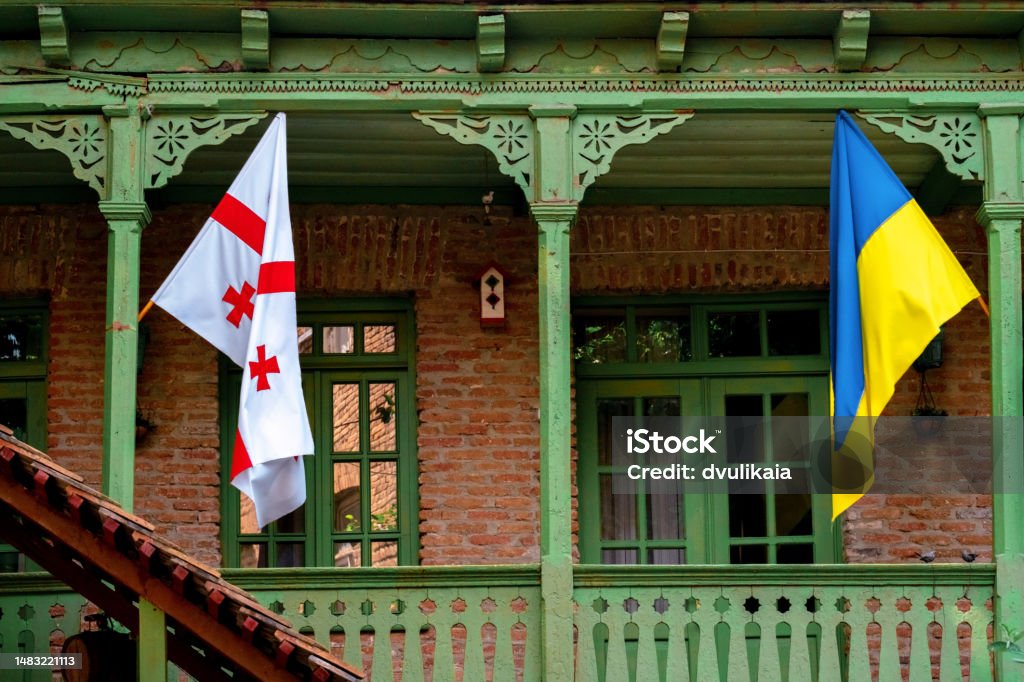 Georgian and Ukrainian flags hanging on the balcony of a classic Georgian wooden house in the center of Tbilisi in Georgia. Georgia - Country Stock Photo