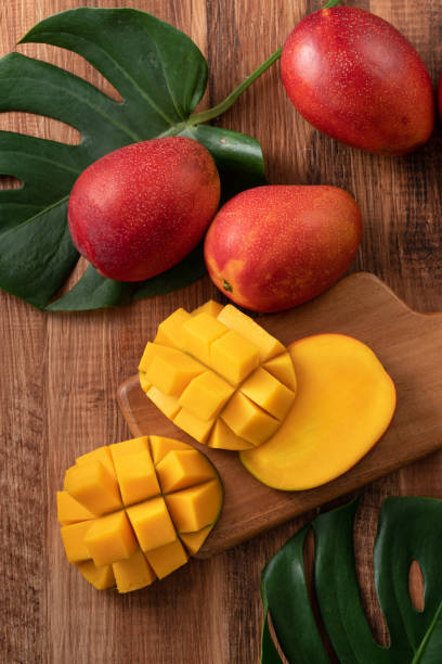 istock Fresh mango fruit with leaves over dark wooden table background. 1483221485