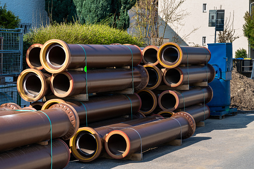 Brown sewer pipes for laying water pipes are stacked on a construction site.
