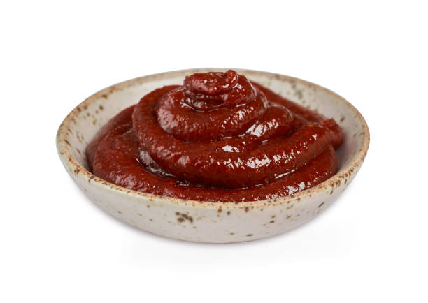 Gochujang or Korean red chili paste in a ceramic bowl isolated on white background with a clipping path. red chili sauce gochujang condiment