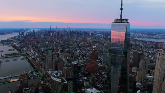 Drone footage around One World Trade Center tower and modern district under a pinky sunset sky