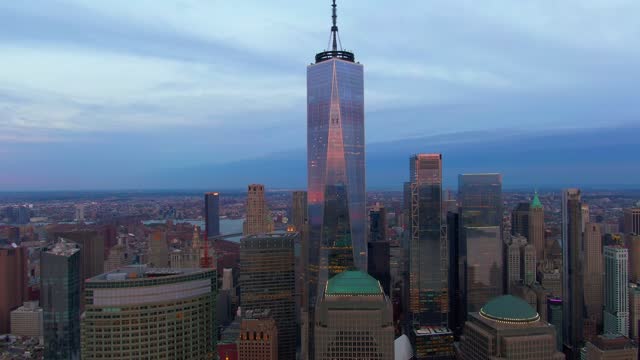 Drone view around One World Trade Center tower and modern buildings under a sunset sky