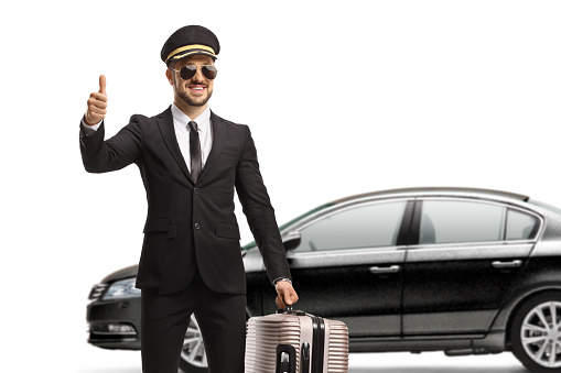 Chauffeur carrying a suitcase and gesturing a thumb up sign isolated on white background
