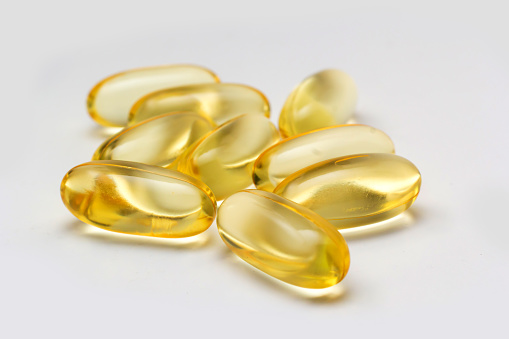 Fish oil capsules omega 3 on light background. Transparent yellow capsules of fish oil.