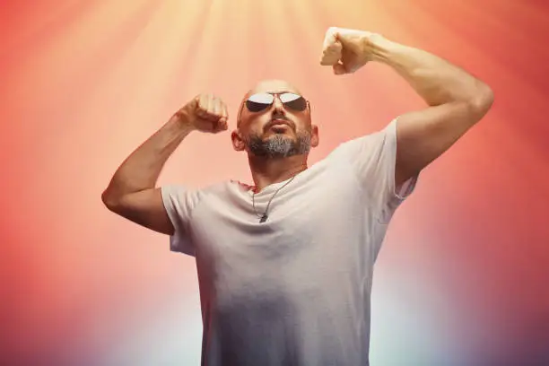 Photo of Man flexing his arms muscles and biceps showing his strength and male power, colorful background